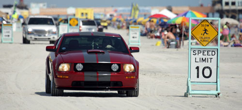 red mustang driving down beach