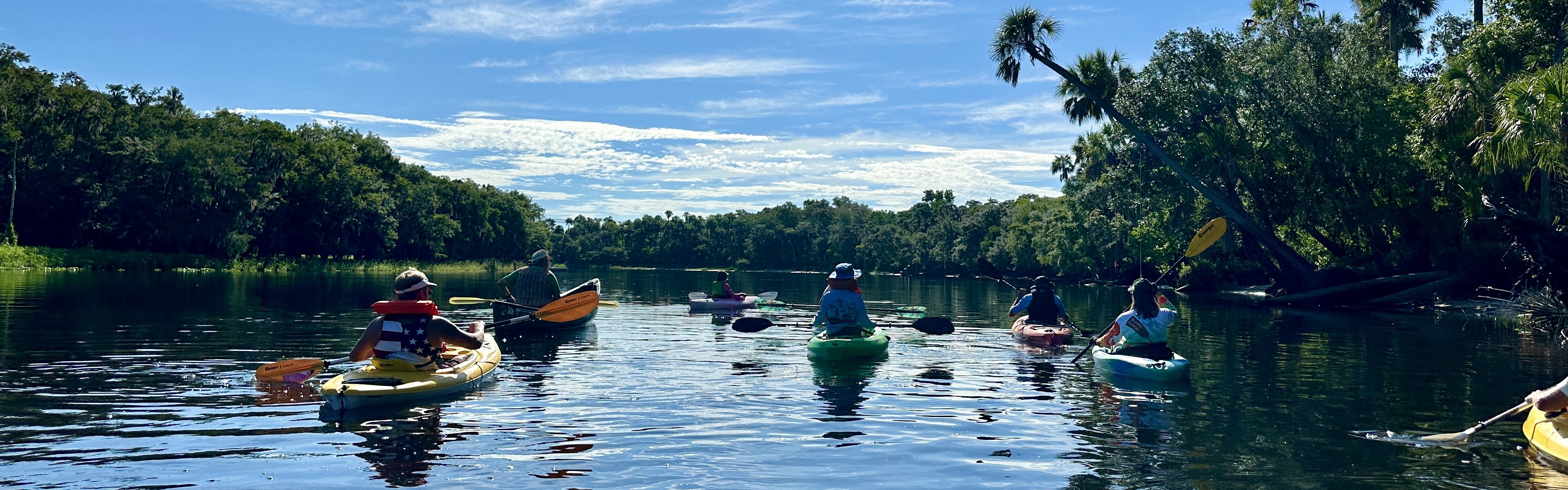 Image of citizens on kayaks, paddling on a river.