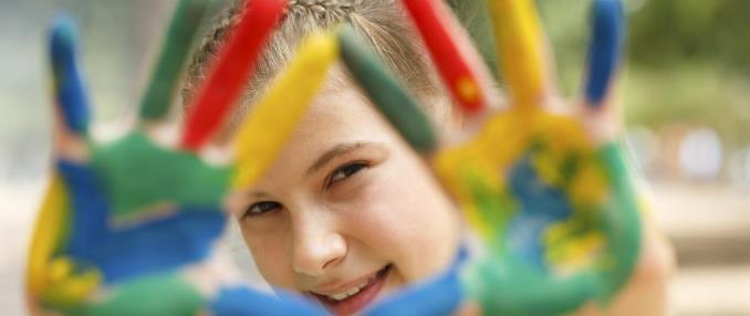 Young girl holding up her hands with paint on them